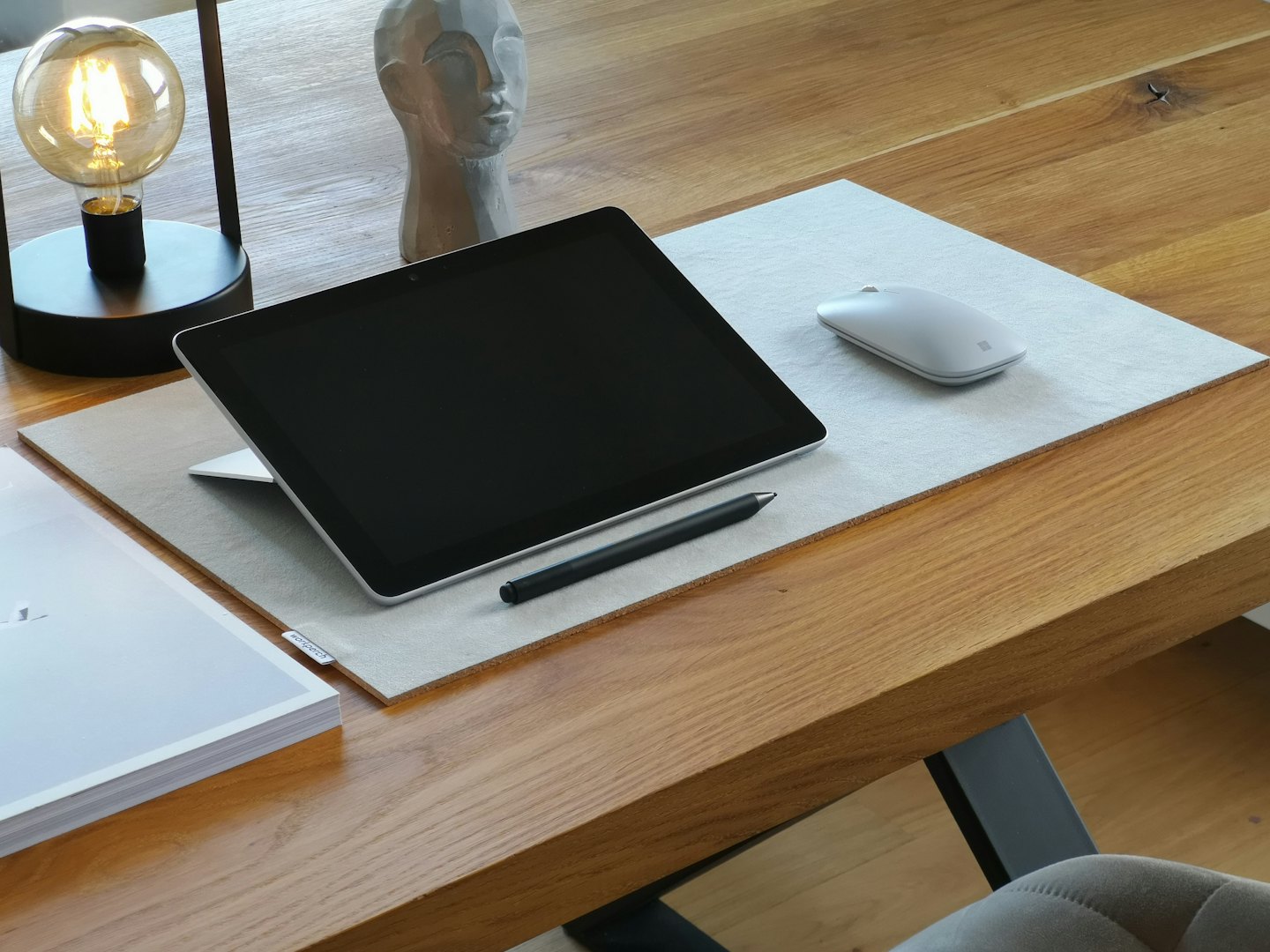 Tablet, stylus, and mouse on a wooden desk.